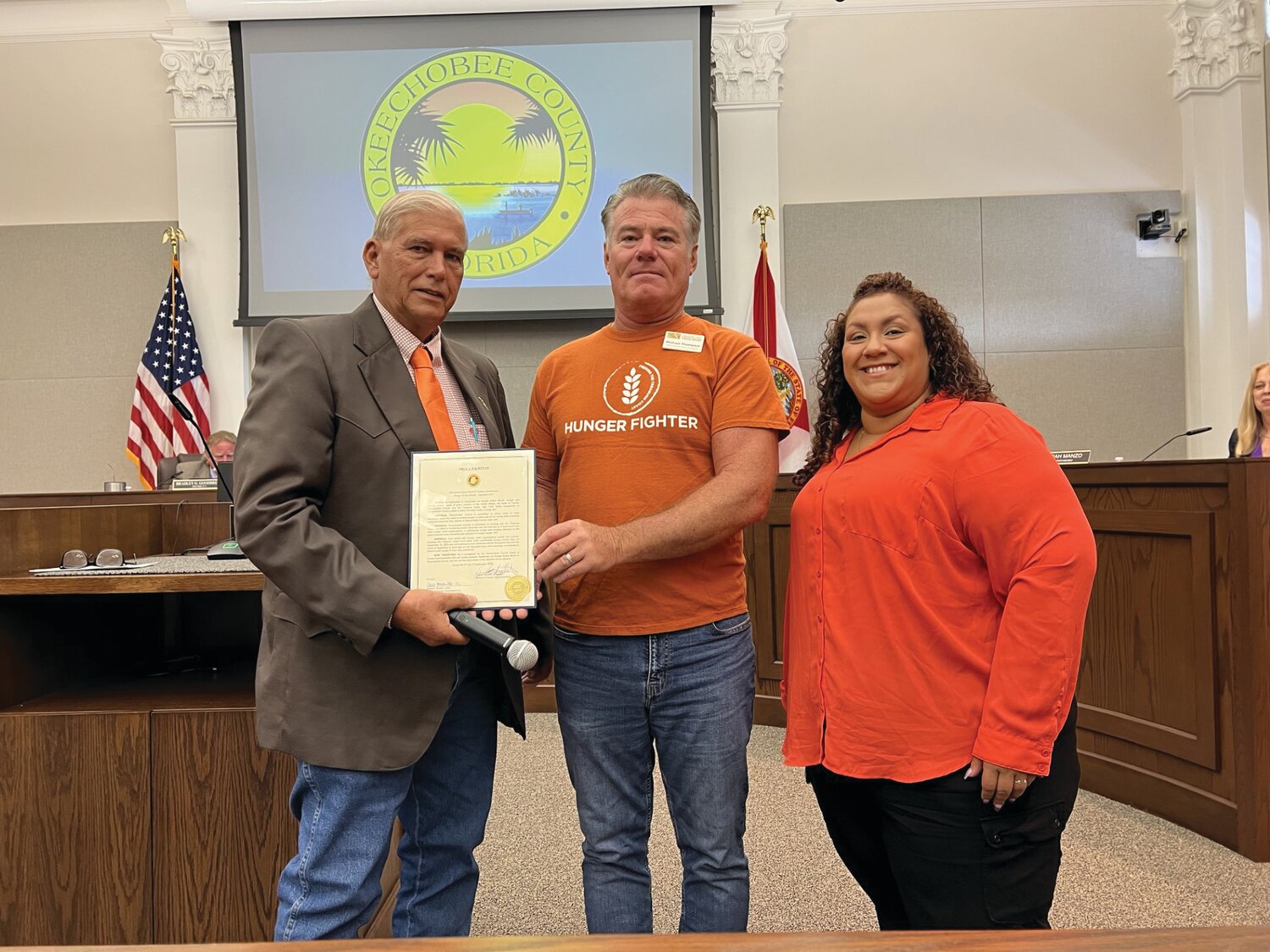 OKEECHOBEE – September is Hunger Action Month in Okeechobee County. At the Sept. 6 meeting, (left to right) Okeechobee County Commission Chairman David Hazellief (left) presented a proclamation to Michael Thompson, Food Procurement Manager for the Treasure Coast Food Bank and Andrea Santos, Retail Store Donation Coordinator. [Photo by Katrina Elsken/Lake Okeechobee News]